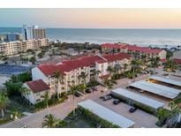 Stunning aerial view of a beachfront condo complex with a red tile roof and beautiful ocean views at sunset at 6236 Midnight Pass Rd # 300, Sarasota, FL 34242