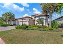 Charming home exterior with a lush tropical landscaped yard and brick driveway at 7044 Whittlebury Trl, Bradenton, FL 34202