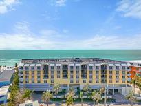 Luxury building with balconies overlooking ocean and beach with rows of palm trees in a sunny landscape at 915 Seaside Dr # 405 Weeks 22-23, Sarasota, FL 34242