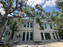 Modern home exterior featuring sleek windows, stucco, and mature trees at 1423 S Shade Ave, Sarasota, FL 34239
