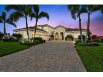 Stunning home featuring a beautifully paved driveway, lush landscaping, and striking curb appeal enhanced by palm trees at sunset at 17003 2Nd E Ave, Bradenton, FL 34212
