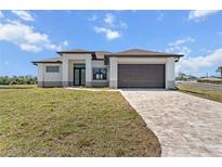 Modern, light gray home with a brown roof, matching brown garage door and a beautifully paved driveway at 197 Rotonda Cir, Rotonda West, FL 33947