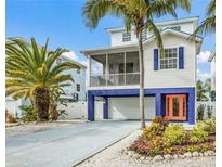 Charming elevated two-story home with a vibrant orange front door and lush landscaping at 316 64Th St, Holmes Beach, FL 34217