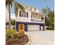 Two-story coastal home featuring a yellow entry door, upper balcony and a convenient ground-level garage at 318 64Th St, Holmes Beach, FL 34217