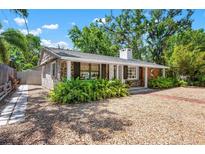 Charming stone home with lush landscaping, a covered porch, and a gravel yard at 528 45Th St, Sarasota, FL 34234