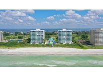 Stunning aerial view of beachfront condos with pristine white sand and clear blue ocean waters at 675 Longboat Club Rd # 23A, Longboat Key, FL 34228