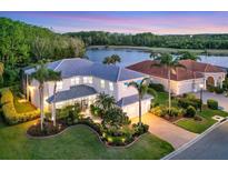 Stunning lakefront home with lush landscaping, a tile roof, and a brick driveway at 7538 Camden Harbour Dr, Bradenton, FL 34212