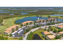 Stunning aerial view of lakeside condos with golf course, mature trees, and convenient covered parking at 7803 Grand Estuary Trl # 102, Bradenton, FL 34212