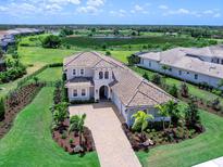 Stunning home featuring a tile roof, brick driveway, lush landscaping, and an expansive green space with a serene pond view at 17114 Verona Pl, Lakewood Ranch, FL 34202
