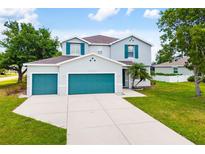 Two-story home featuring a lush lawn, a two car garage, and gray facade with turquoise shutters at 25364 Tether Ln, Punta Gorda, FL 33983