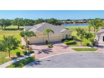 Stunning single-story home featuring lush landscaping, a brick driveway, and a three-car garage at 302 Crystal Downs Ct, Sun City Center, FL 33573