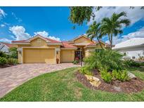 Beautiful home with red tile roof, lush landscaping, brick paver driveway, and a two-car garage at 410 Wellington, Venice, FL 34292