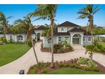 Elegant two-story waterfront home with lush landscaping and a circular brick driveway lined with palm trees at 4355 Pompano Ln, Palmetto, FL 34221