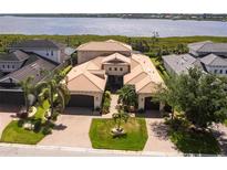 Expansive estate with a red tile roof, lush landscaping, and an adjacent waterway view at 5502 Tidewater Preserve Blvd, Bradenton, FL 34208