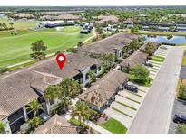 Aerial view of condo building with golf course and pond nearby, featuring tiled roof and well-manicured landscaping at 5528 Palmer Cir # 204, Lakewood Ranch, FL 34211