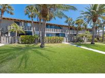 Beautiful two-story condo building with palm trees and a well-manicured lawn in a tropical setting at 6400 Flotilla Dr # 87, Holmes Beach, FL 34217