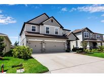 Two-story home featuring a three-car garage, neutral paint, and well-manicured lawn at 8346 Abalone Loop, Parrish, FL 34219