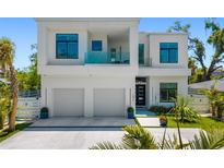 Modern two-story home with a two-car garage, balcony with glass railings, and manicured landscaping at 1842 Kenilworth St, Sarasota, FL 34231