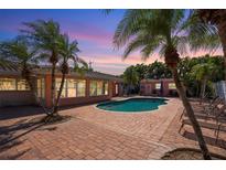Inviting backyard with swimming pool, brick patio, lush landscaping and lounge chairs at 2609 Webber St, Sarasota, FL 34239