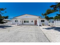 Charming white single-story home with a red front door, covered parking and well-kept landscaping at 420 63Rd St # B East, Holmes Beach, FL 34217