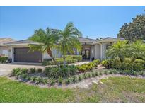 Charming home with lush landscaping, palm trees, and a tile roof on a sunny day at 5554 Eastwind Dr, Sarasota, FL 34233