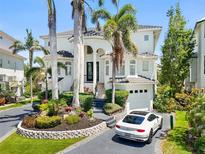 Stunning two-story waterfront home with lush landscaping, elegant architectural details, and a circular driveway at 7118 Hawks Harbor Cir, Bradenton, FL 34207