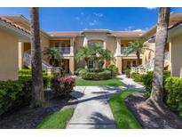 Inviting condo exterior with well-maintained landscaping, tiled roof, and walkway leading to the entrance at 7155 Boca Grove Pl # 102, Lakewood Ranch, FL 34202