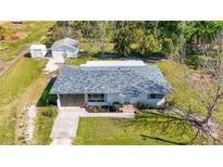 Charming home featuring a well-maintained lawn, flower beds, driveway, and a detached garage, creating curb appeal at 80 Liles St, Terra Ceia, FL 34250
