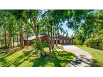 Stunning single Gathering home with a metal roof, mature trees, and a welcoming circular driveway at 801 Oak Vista Dr, Sarasota, FL 34232
