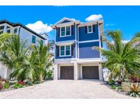 Beautiful two-story blue home featuring a gravel driveway, landscaping, and a two-car garage at 201 Bay N Dr, Bradenton Beach, FL 34217