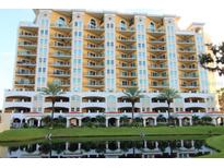 Beautiful multi-story condo building with balconies, palm trees, and pond reflections at 501 Haben Blvd # 704, Palmetto, FL 34221