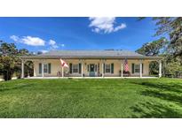 Charming single-story home featuring a large porch, green lawn, and a cheerful blue front door at 6365 Jim Davis Rd, Parrish, FL 34219