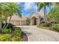 Charming home featuring a brick driveway, three-car garage, and lush landscaping at 7011 Portmarnock Pl, Lakewood Ranch, FL 34202