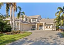 A charming two-story home with a well-manicured lawn, palm trees, and a wide driveway at 1016 91St Nw St, Bradenton, FL 34209