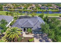 A sprawling waterfront home featuring a dark roof, lush landscaping, and waterway views at 10411 Winding Stream Way, Bradenton, FL 34212