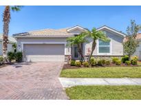 Charming single-story home with a well-maintained lawn, brick driveway, and lush tropical landscaping at 11702 Anhinga Avenue, Venice, FL 34292