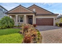 Charming single-story home featuring a well-manicured lawn, brick driveway, and two-car garage at 14265 17Th E Ct, Parrish, FL 34219