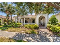 Charming home featuring a welcoming front porch, arched entryway, and beautifully landscaped front yard at 1520 Dorgali Dr, Sarasota, FL 34238