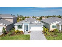 Charming single Gathering home with a well manicured lawn, stone driveway, and beautiful plants at 18525 Midsummer Pl, Venice, FL 34293