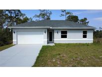 Charming single-story home featuring a two-car garage, well-maintained lawn, and neutral-toned exterior paint at 2163 Blaser St, Port Charlotte, FL 33980
