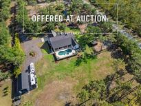 Expansive aerial view of a home featuring a large lawn, pool, wooded perimeter and additional garage or storage space at 25305 83Rd E Ave, Myakka City, FL 34251
