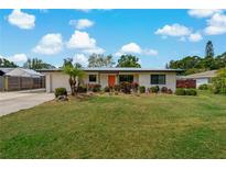 Charming single-story home featuring a landscaped front yard and an inviting orange front door at 2708 Fort Worth St, Sarasota, FL 34231