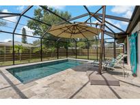 Relaxing screened pool area with clear blue water, lounge chairs, and umbrella for shade on a stone tile deck at 2708 Fort Worth St, Sarasota, FL 34231