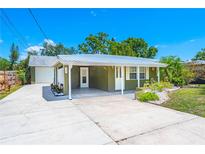 Charming one-story home with a metal roof, carport, and neatly landscaped front yard on a sunny day at 3427 Cambridge Dr, Sarasota, FL 34232