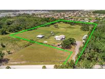 Expansive aerial view showcasing the home, surrounding acreage, and outbuildings within a green-lined property boundary at 5235 Spencer Parrish Rd, Parrish, FL 34219