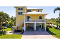 Bright yellow raised stilt home featuring covered parking and a charming front porch at 6802 68Th E Ave, Bradenton, FL 34203
