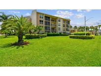 Beautiful condo exterior with well-manicured green lawn and tropical landscaping at 845 Benjamin Franklin Dr # 101, Sarasota, FL 34236