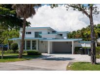 Charming two-story home with well-maintained landscaping, a carport, and a concrete driveway at 91 Avenida Veneccia, Sarasota, FL 34242