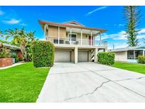 Charming two-story home featuring a covered balcony, two-car garage, and well-manicured lawn at 216 Palmetto Ave, Anna Maria, FL 34216