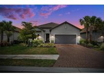 Charming home featuring a lush, landscaped front yard, brick paver driveway, and two-car garage at 6266 Mesa Gln, Bradenton, FL 34203
